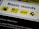 A close-up of a poster with the heading 'Basic needs' and four icons. Each icon is placed on a yellow background: a gas pump, cutlery with a wine glass, a bed, and a letter E on a tilted square.
