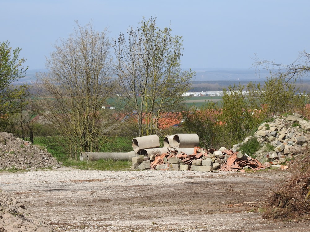 a pile of pipes sitting on top of a dirt field