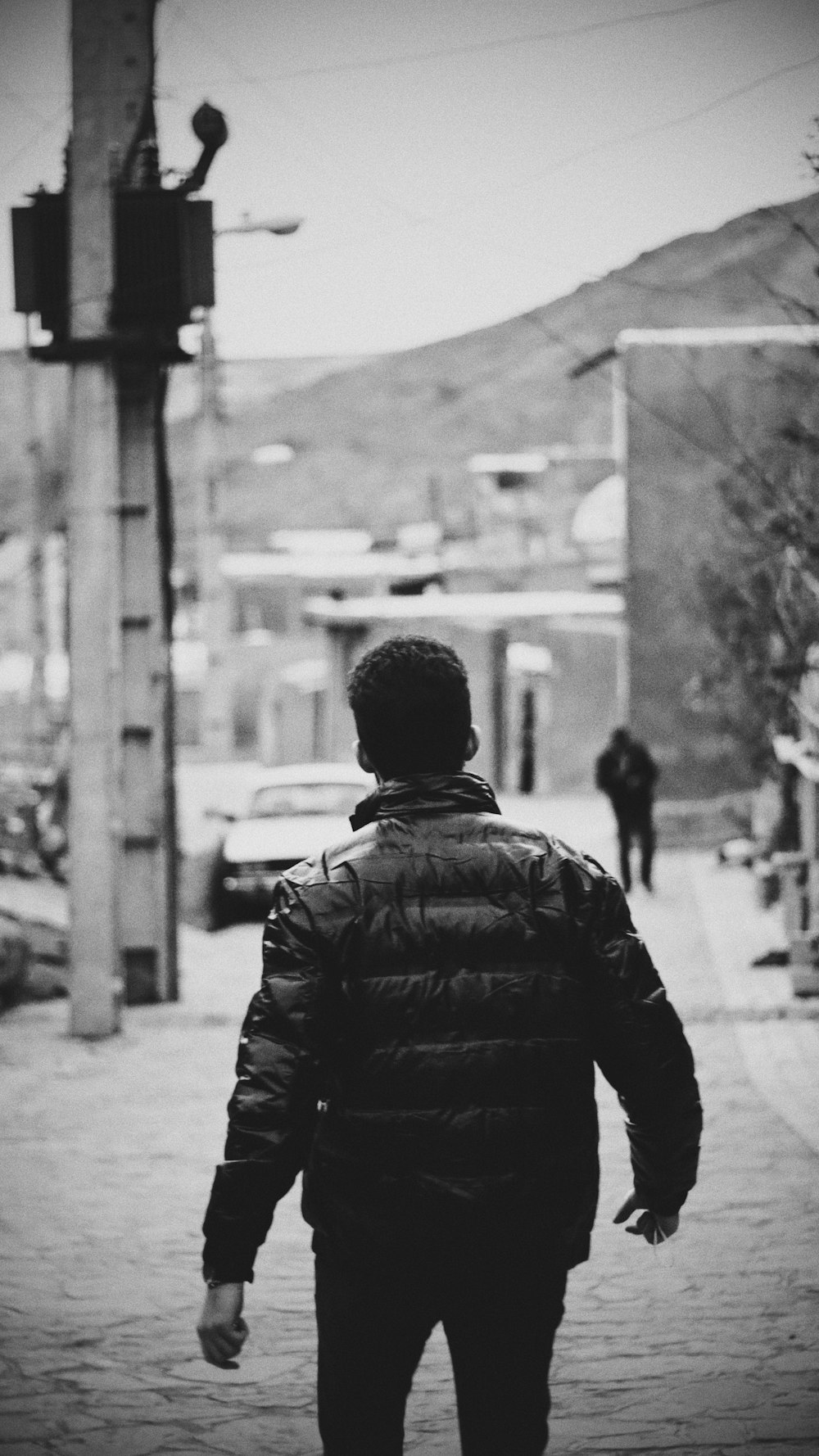 a man walking down a street next to a traffic light