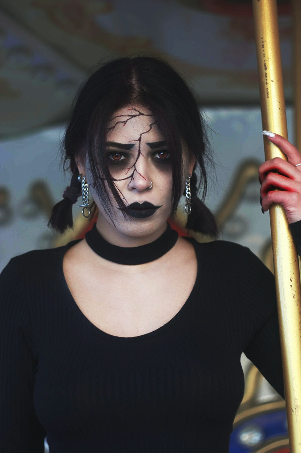 a woman with black makeup holding a pole