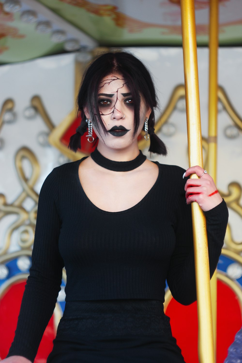 a woman with black makeup holding a pole