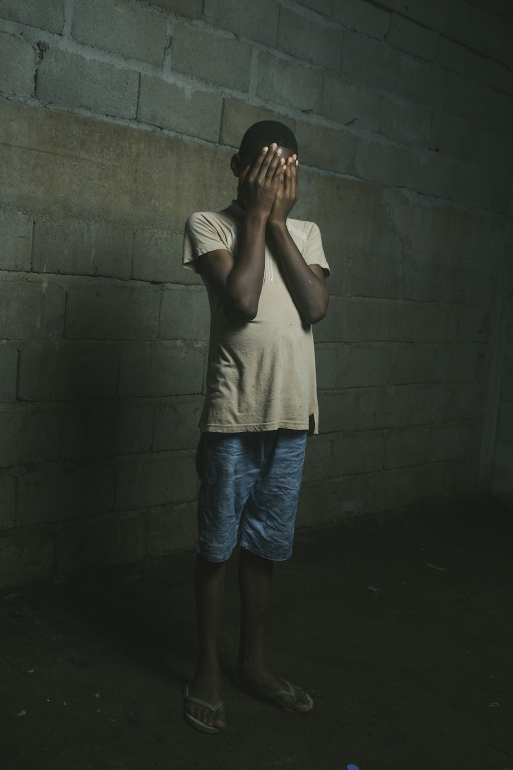 a young boy covers his face with his hands