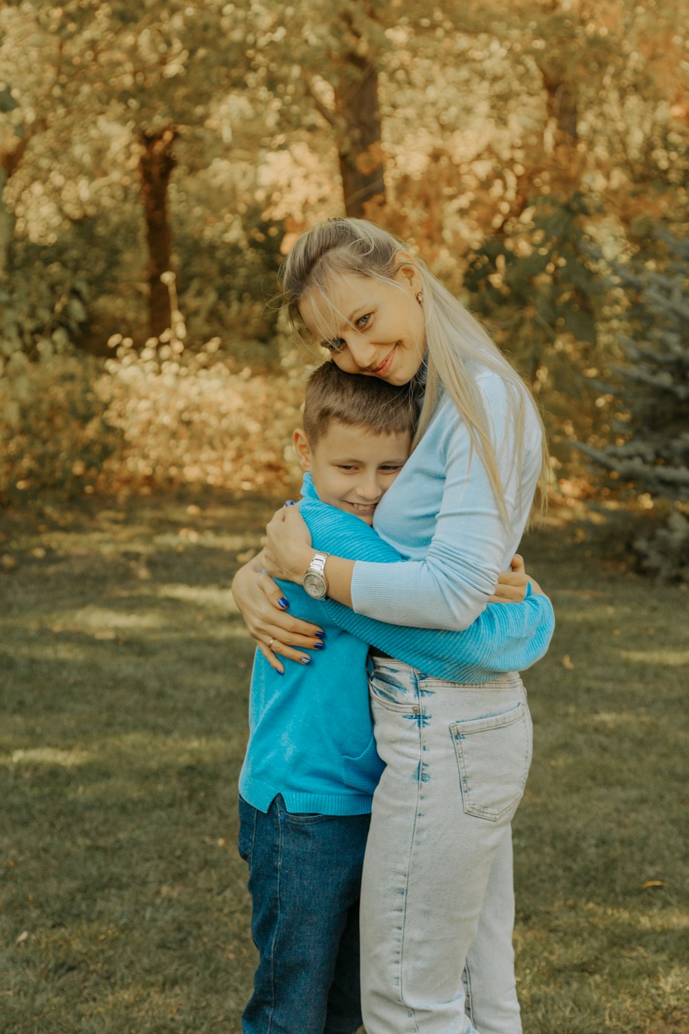 a woman hugging a boy in a field