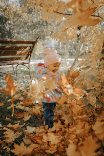 a little girl standing in a pile of leaves