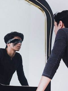 a man in a blindfold looking at himself in a mirror