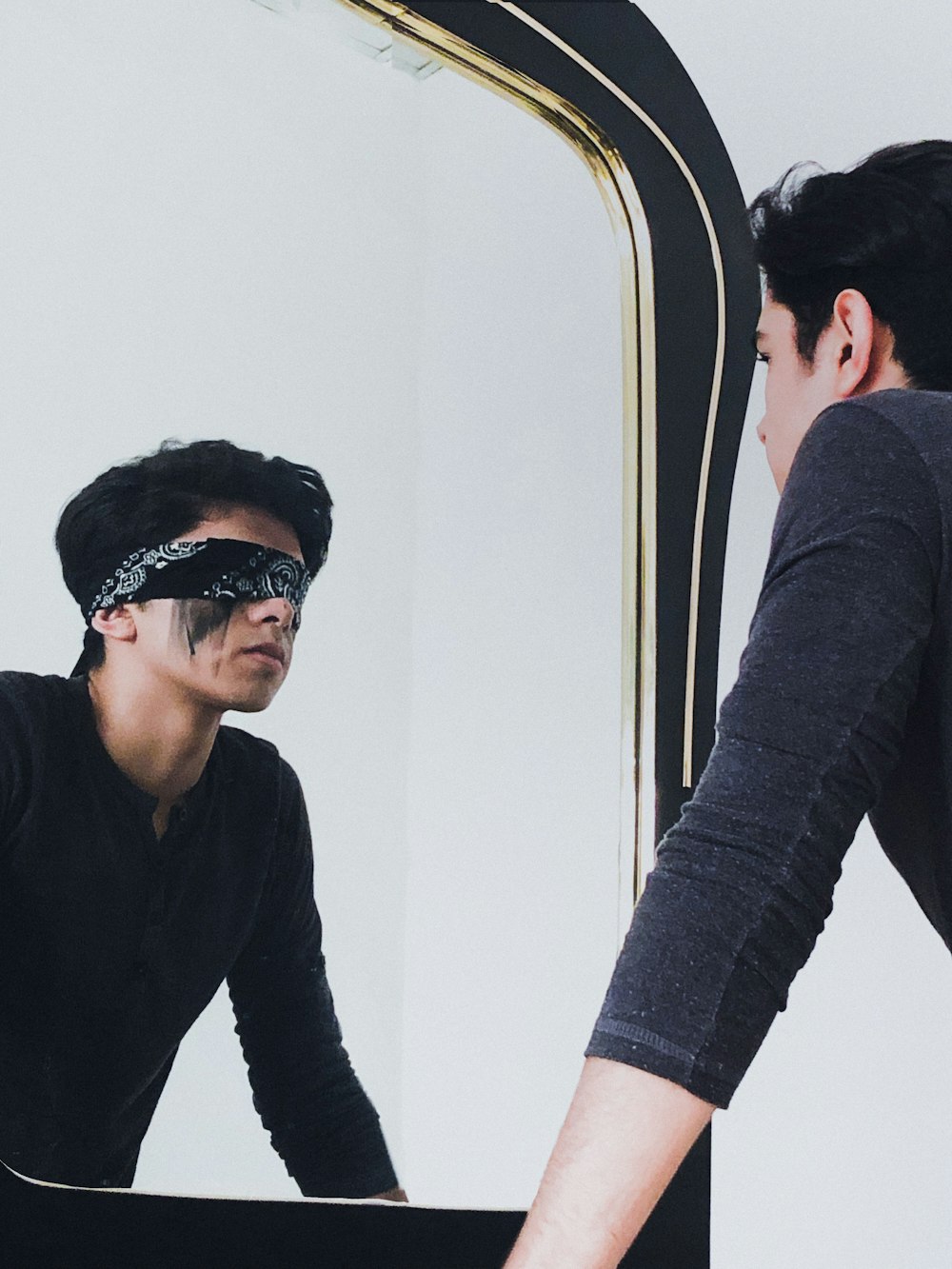 a man in a blindfold looking at himself in a mirror