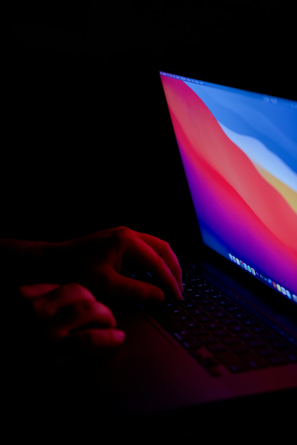 a person typing on a laptop in the dark