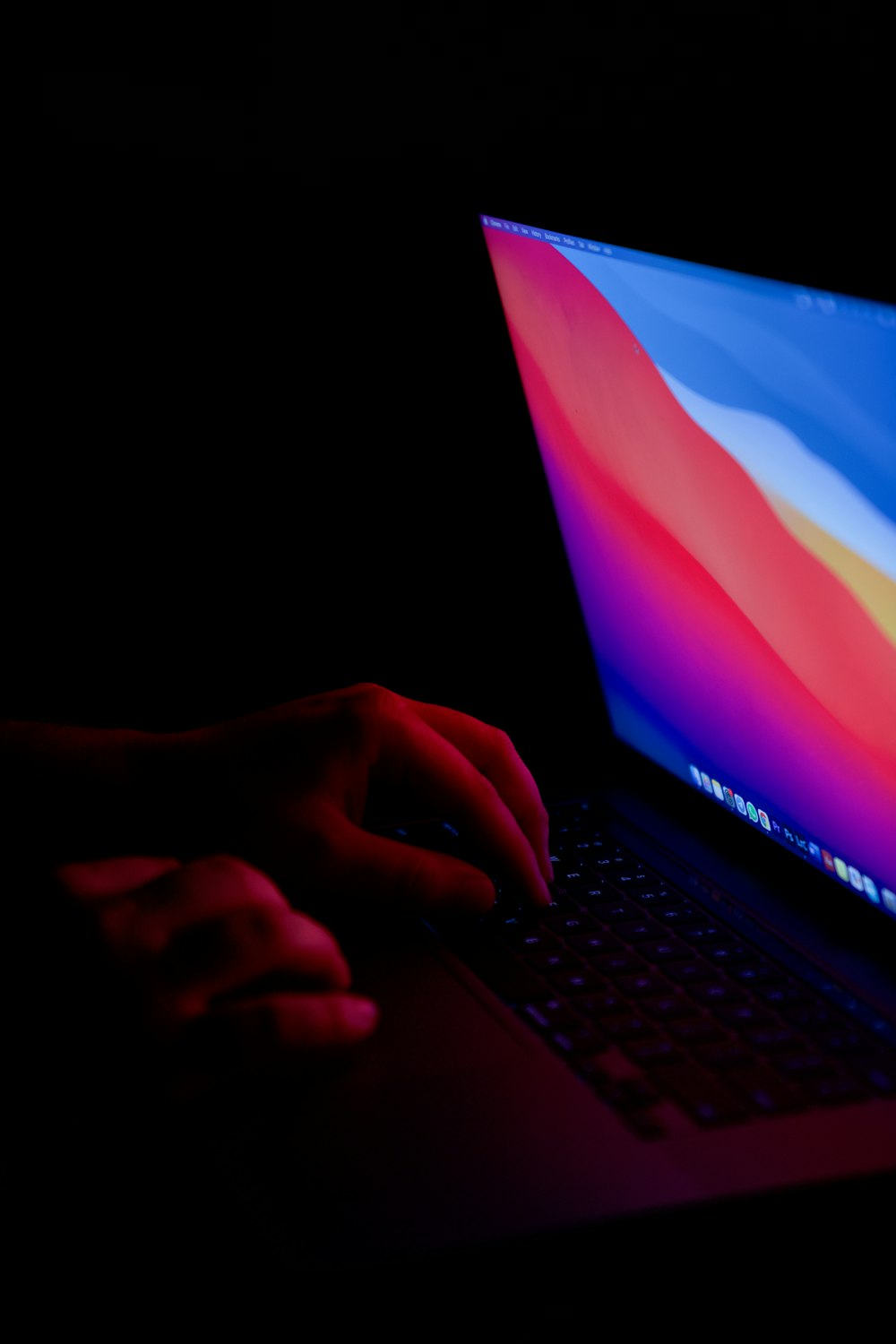 Una persona escribiendo en una computadora portátil en la oscuridad