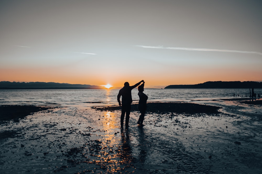 a couple of people standing on top of a beach