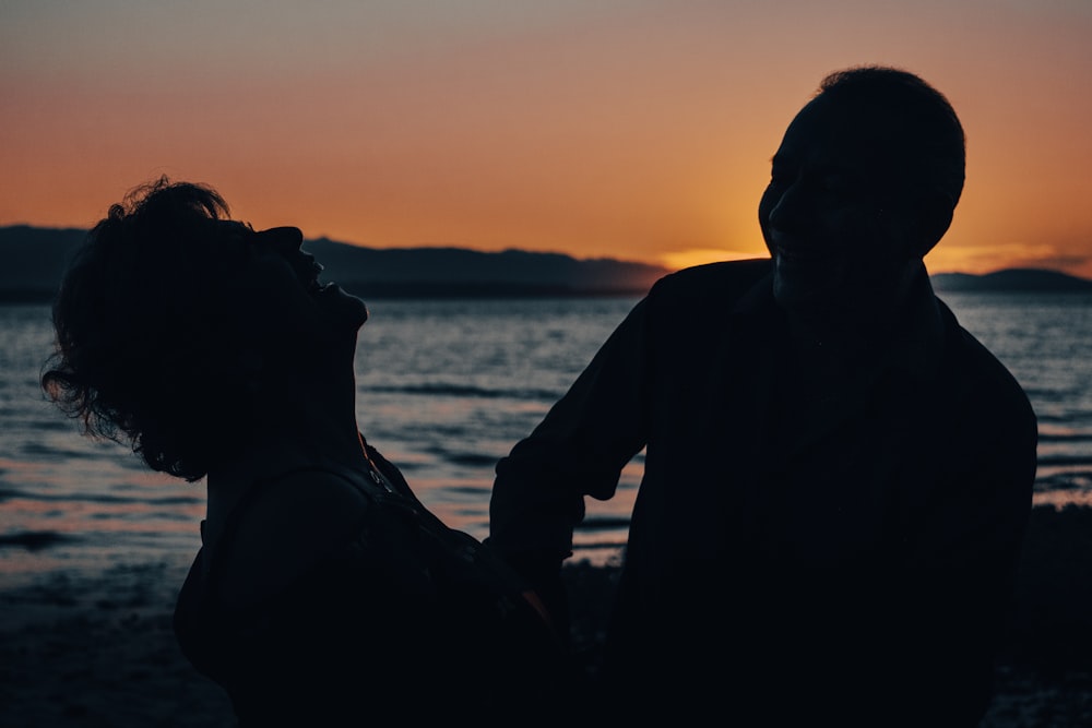 a couple of people standing next to a body of water