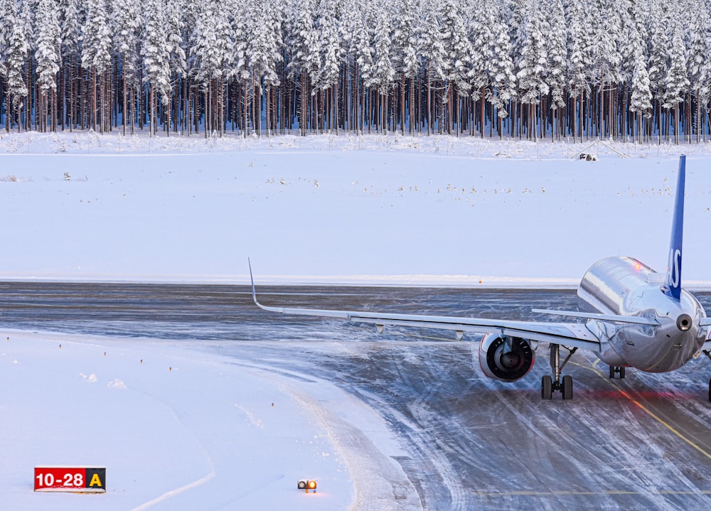 an airplane on a snowy runway with trees in the background