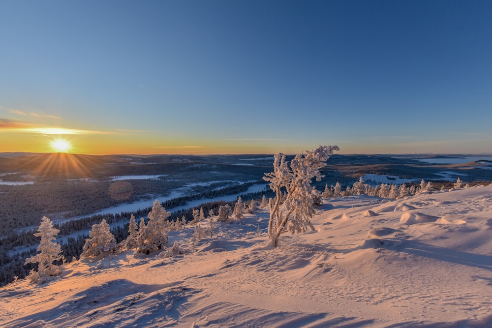 the sun is setting over a snowy mountain