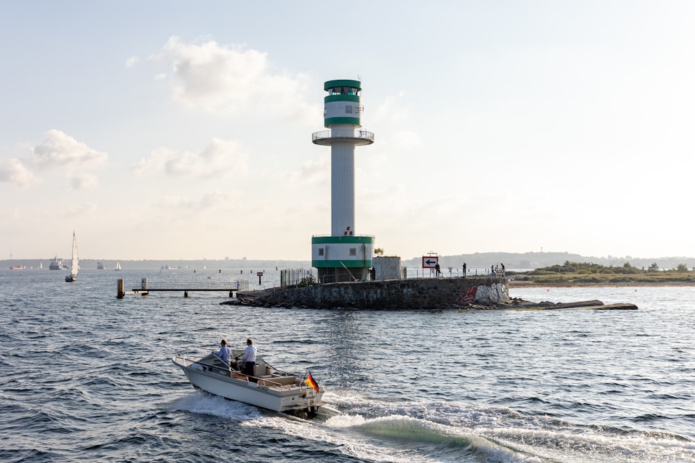 a small boat in the water near a light house