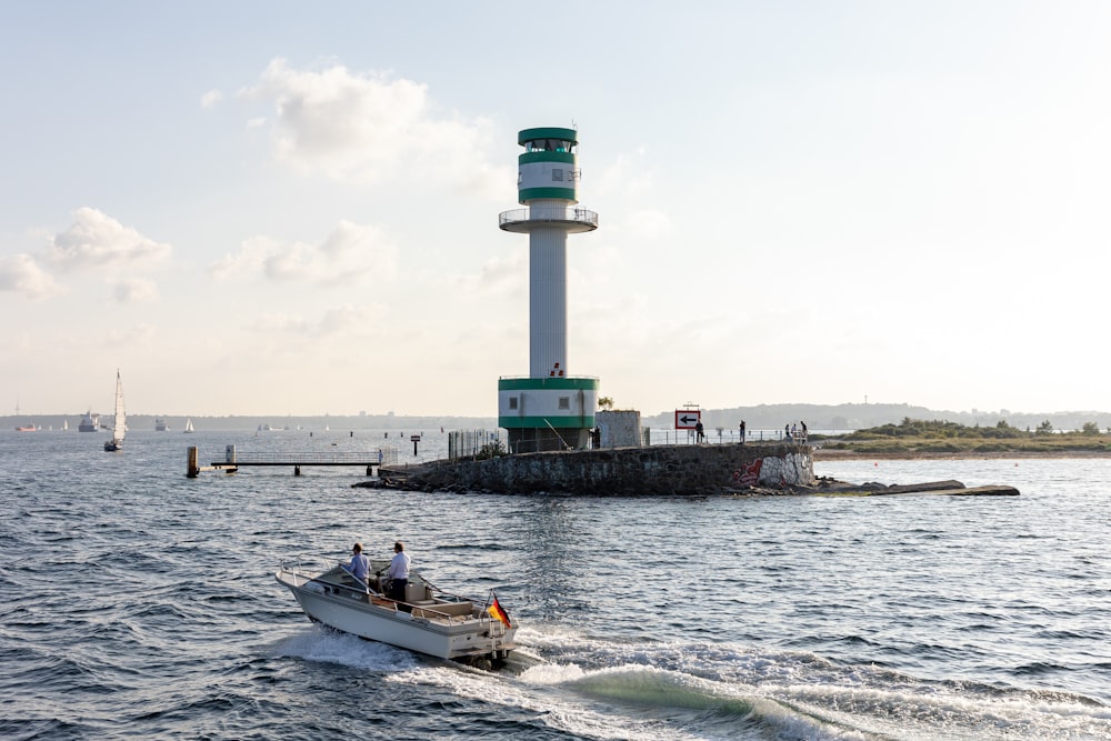 Un petit bateau dans l’eau près d’un phare