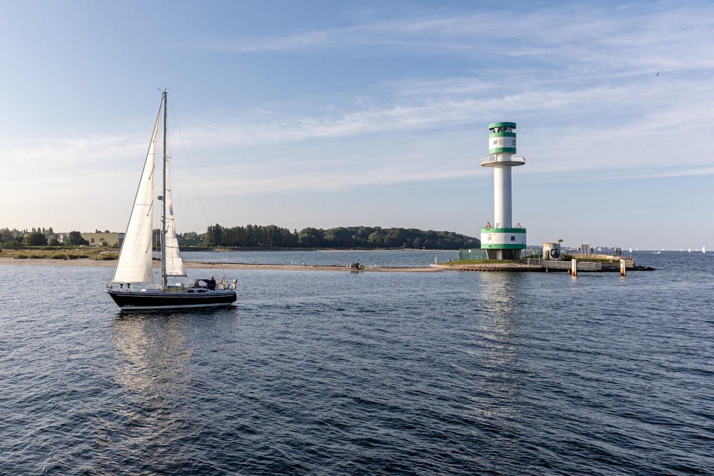 a sailboat in the water near a light house