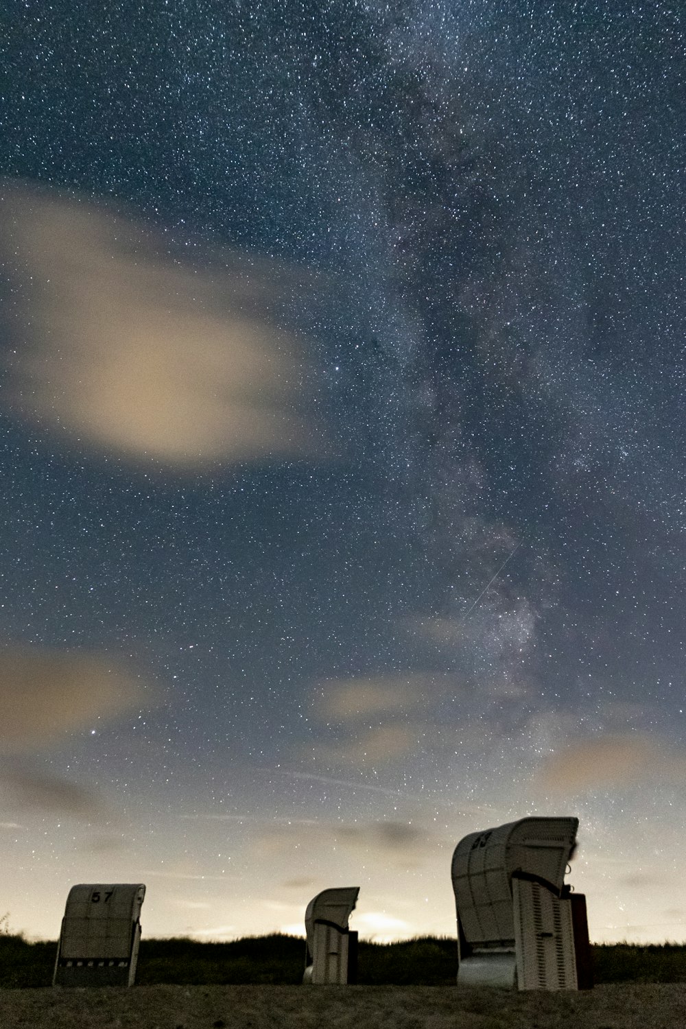 a group of chairs sitting on top of a field under a sky filled with stars