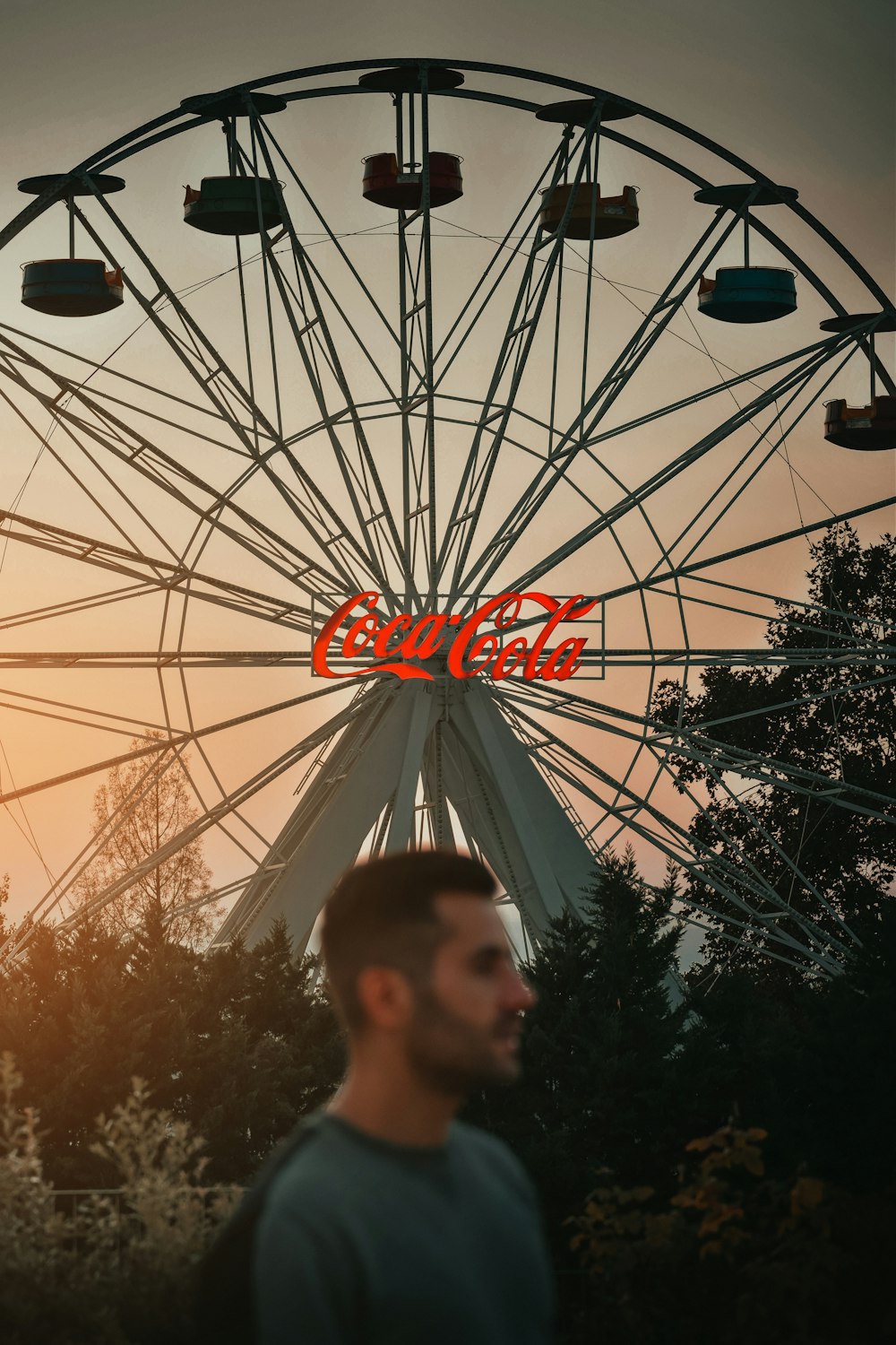 a man standing in front of a ferris wheel