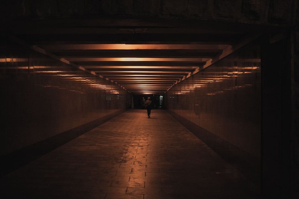 a person walking down a long hallway at night