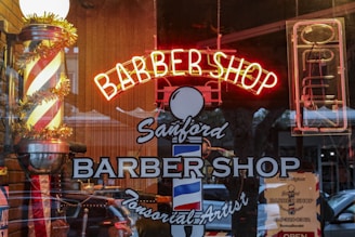 a barber shop with a neon sign in the window