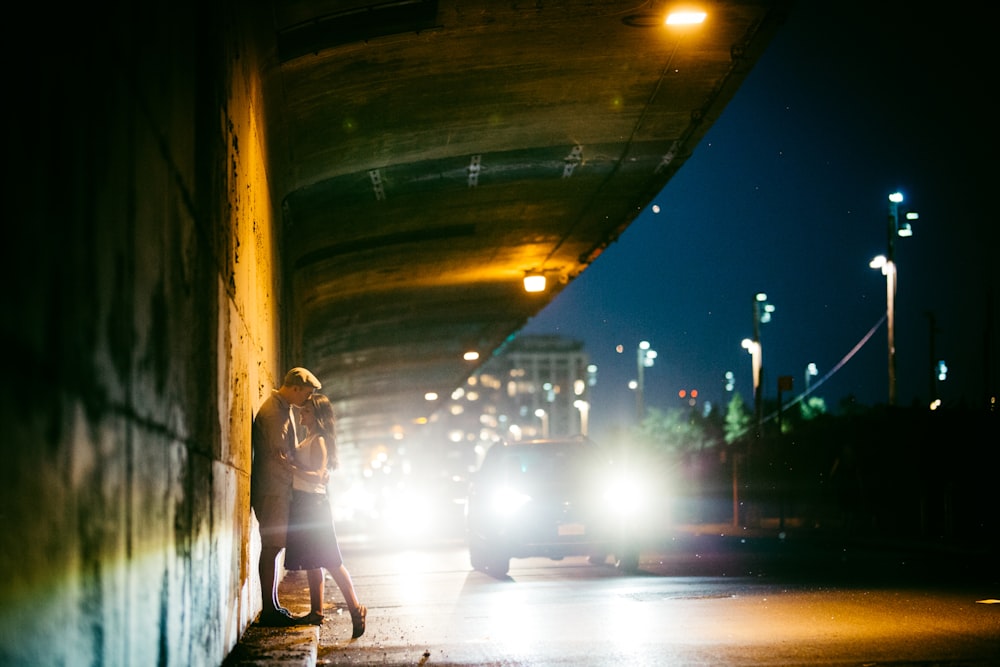 a couple kissing under a bridge at night