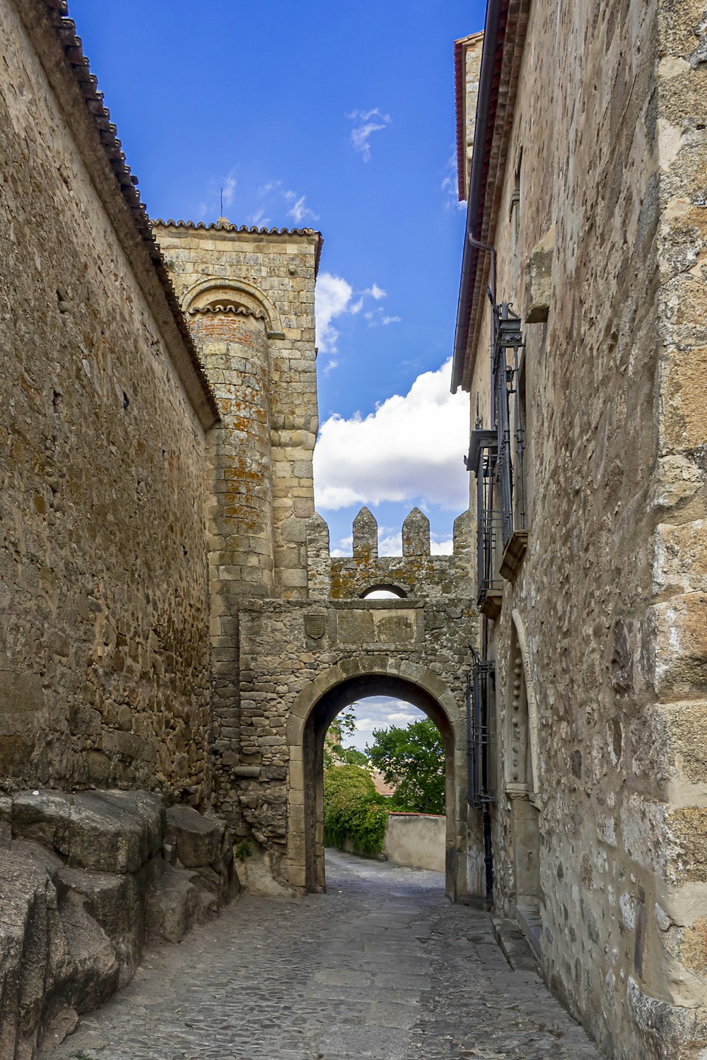 uma rua estreita com um arco de pedra entre dois edifícios