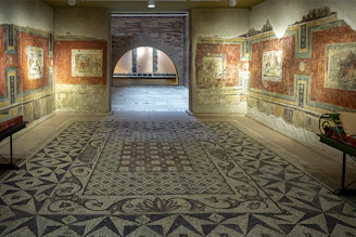 A serene hallway in the museum with blue and white mosaic floors and framed artworks lining the walls.