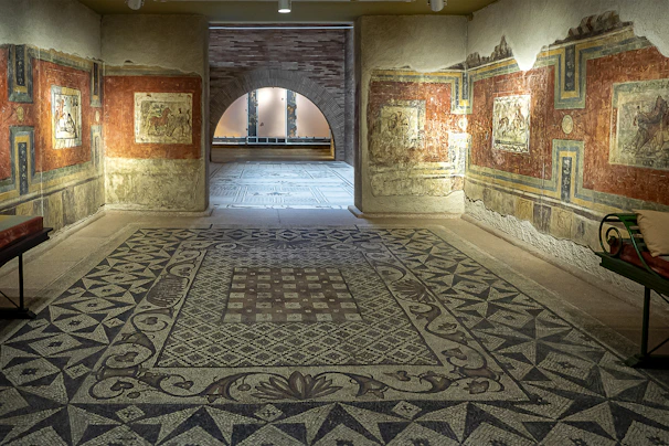 A serene hallway in the museum with blue and white mosaic floors and framed artworks lining the walls.