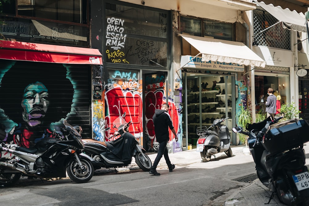 a man walking down a street next to parked motorcycles