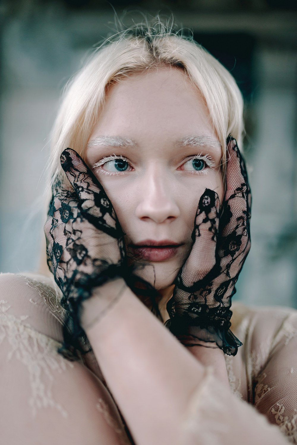 a woman with white hair and blue eyes wearing black gloves