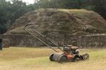 a lawn mower sitting on top of a dry grass field