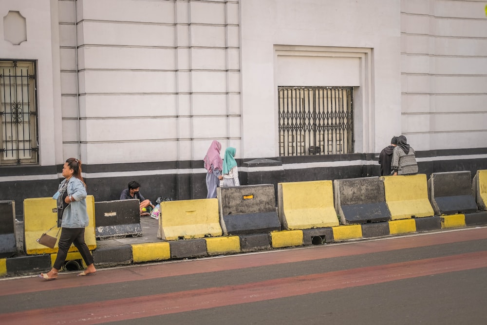 a group of people walking down a street next to a yellow barricade