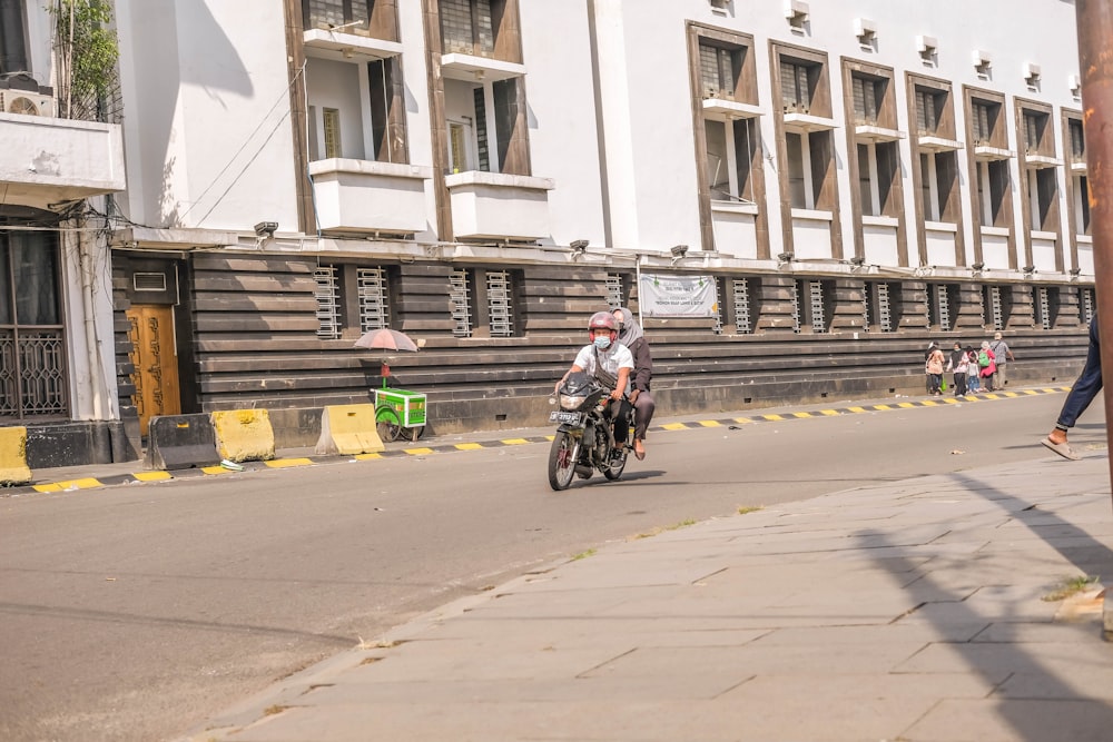 a man riding a motorcycle down a street next to tall buildings