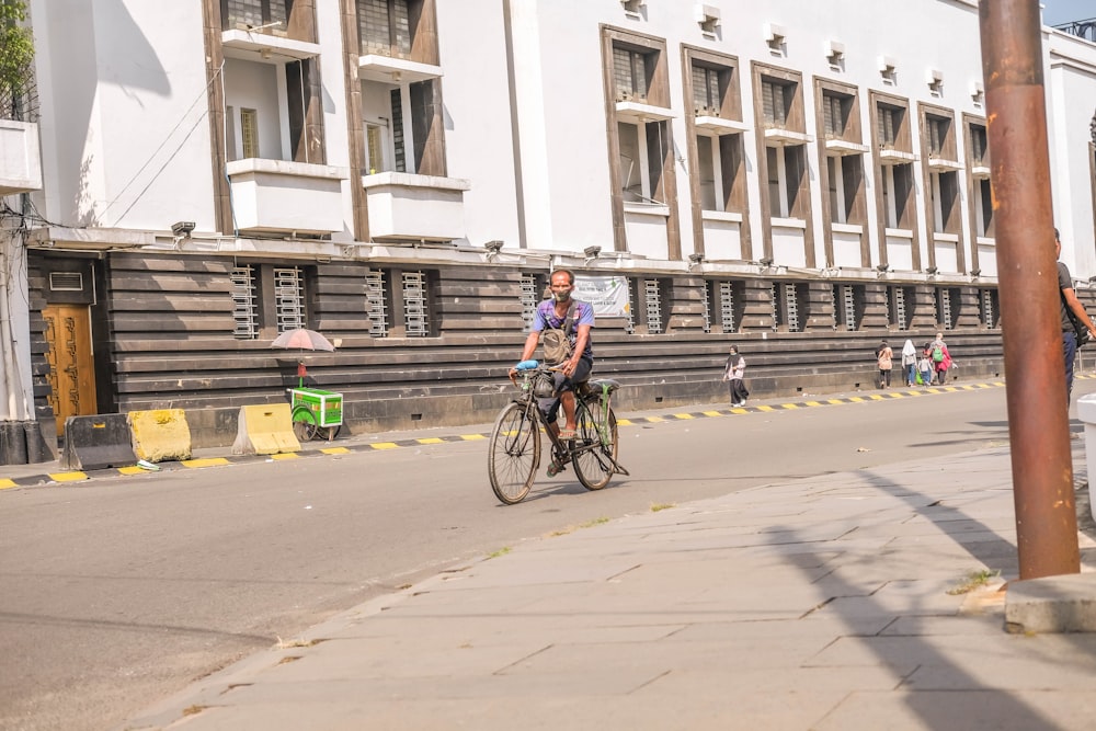 a man riding a bike down a street next to a tall building