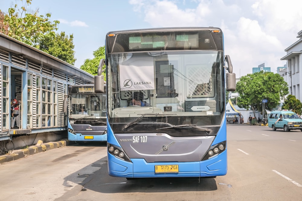 a blue and grey bus parked on the side of the road