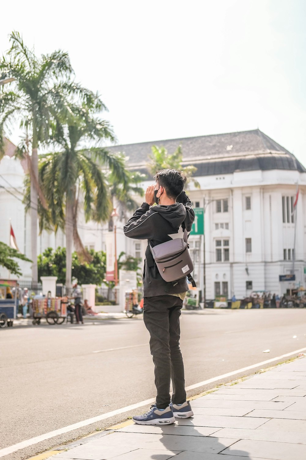 a man standing on the side of a street talking on a cell phone