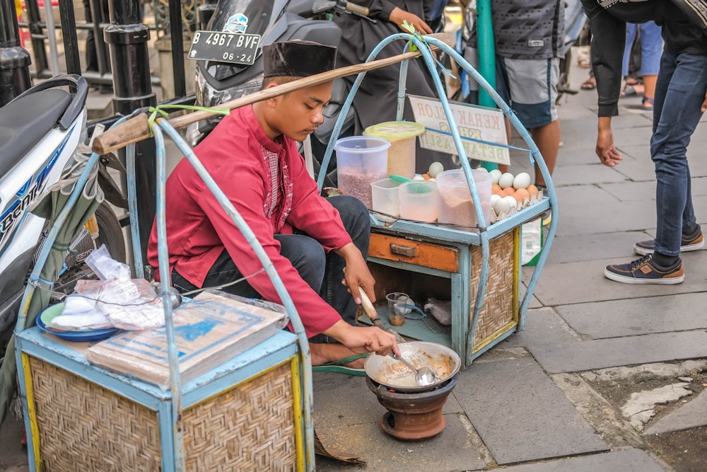 a man sitting on the ground cooking food