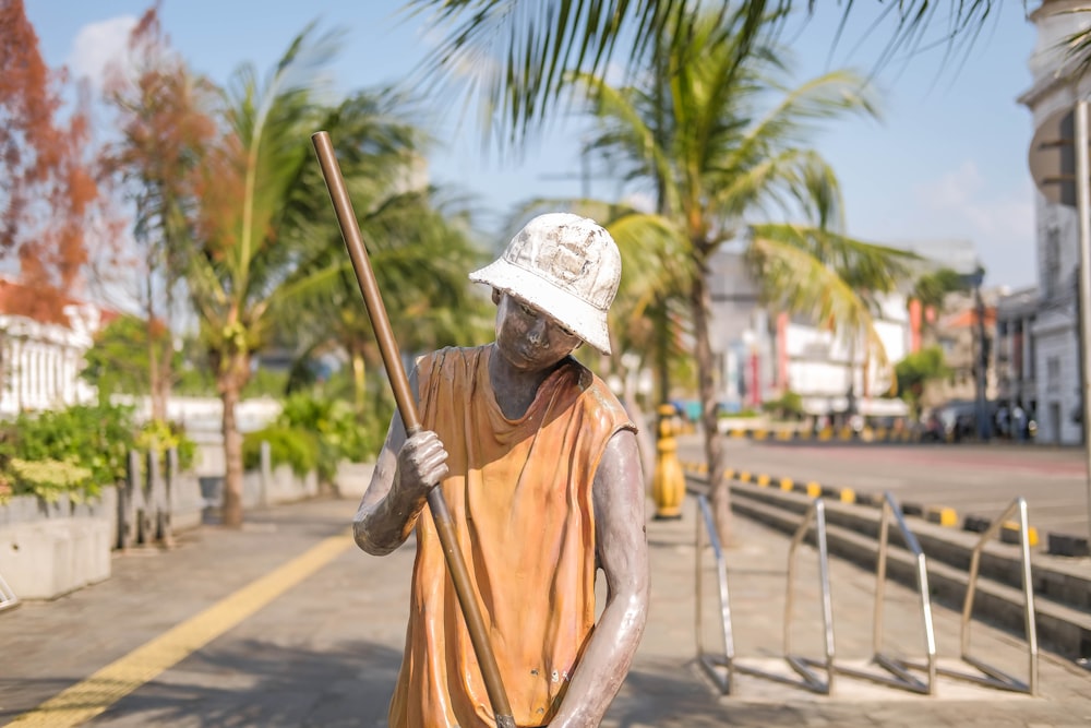 a statue of a man holding a stick on a street