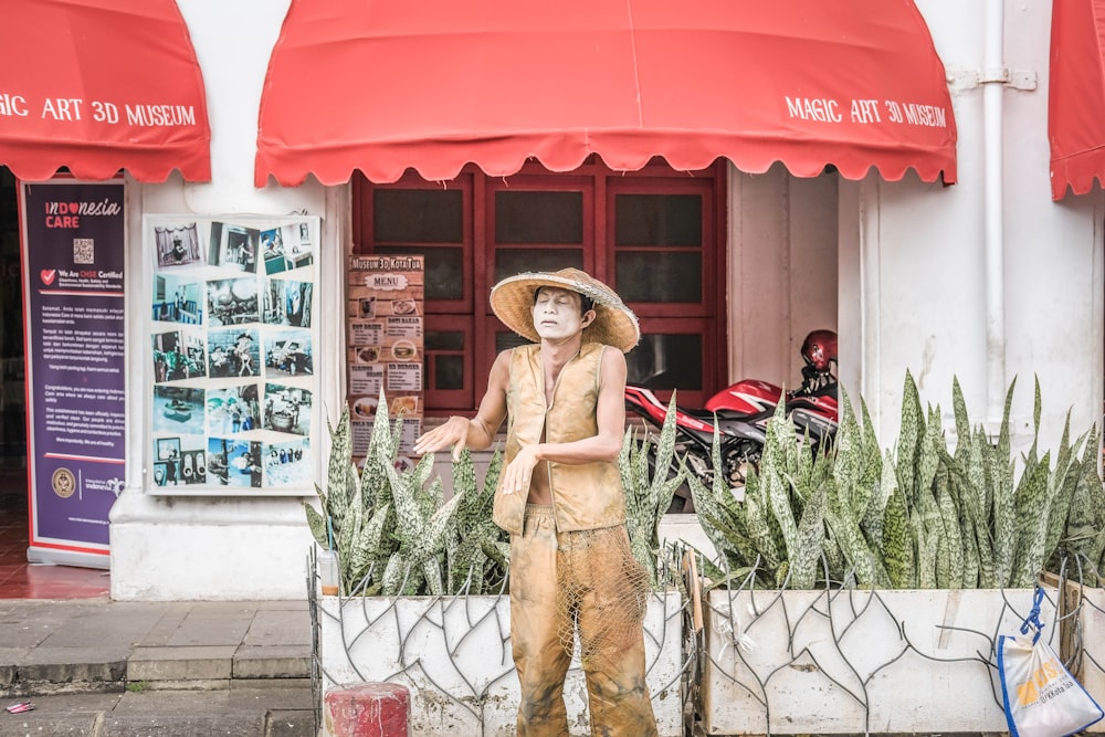 Una statua di un uomo con un cappello di paglia di fronte a un negozio