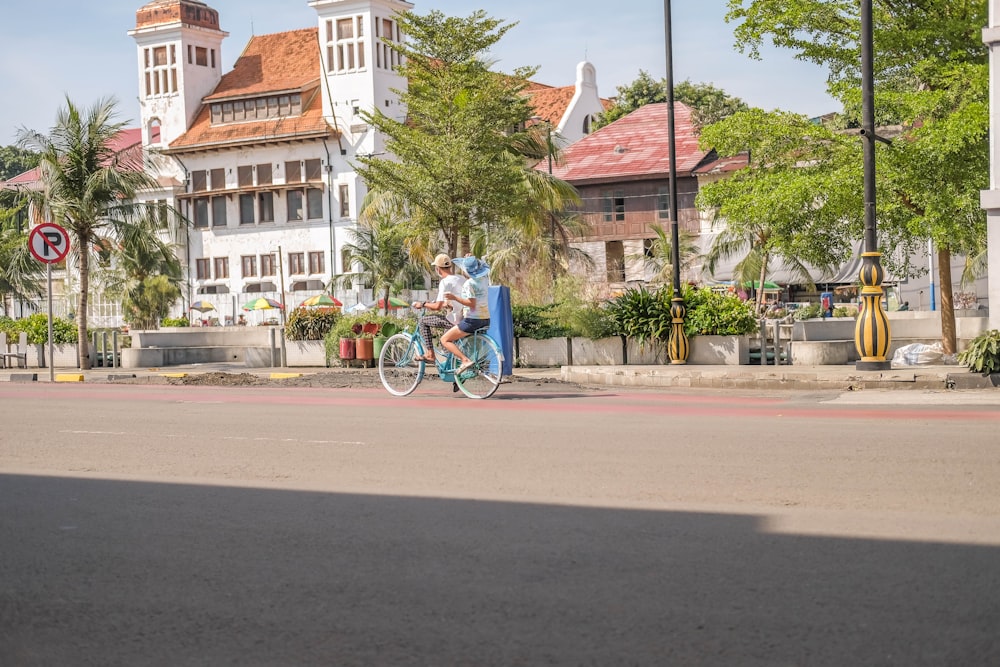 a man and a woman riding a bike down a street