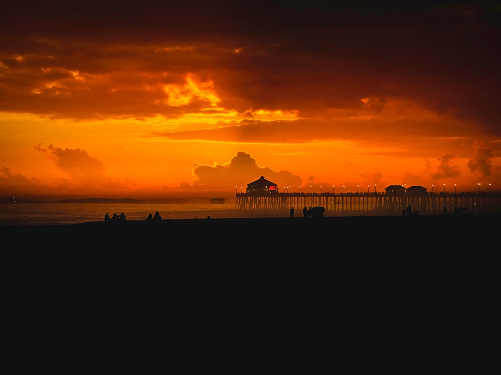 a sunset over the ocean with a pier in the distance