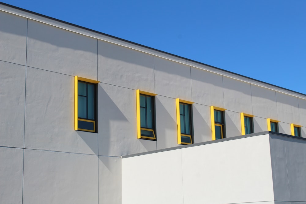 a white building with yellow windows and a blue sky