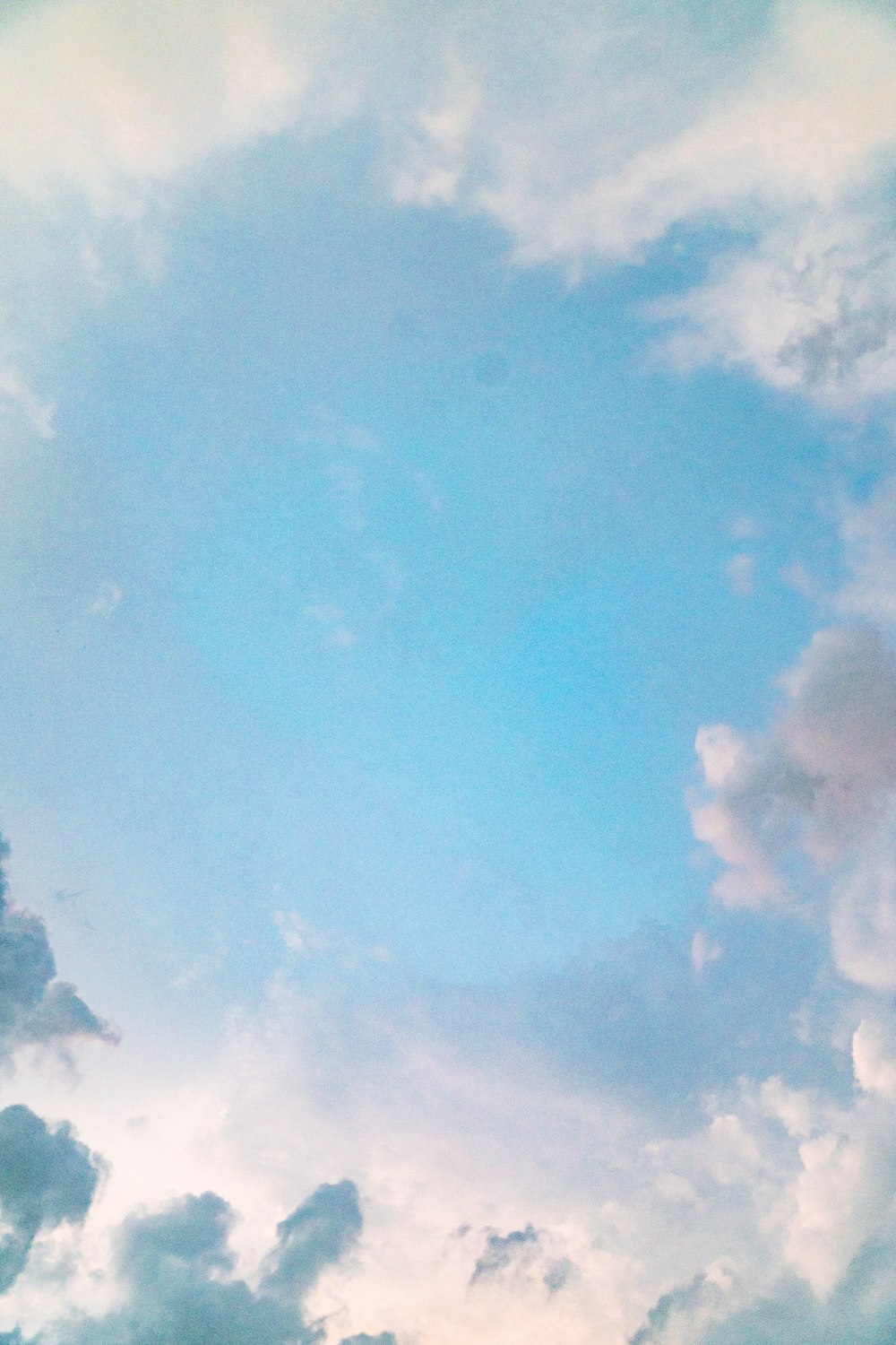 a plane flying through a cloudy blue sky