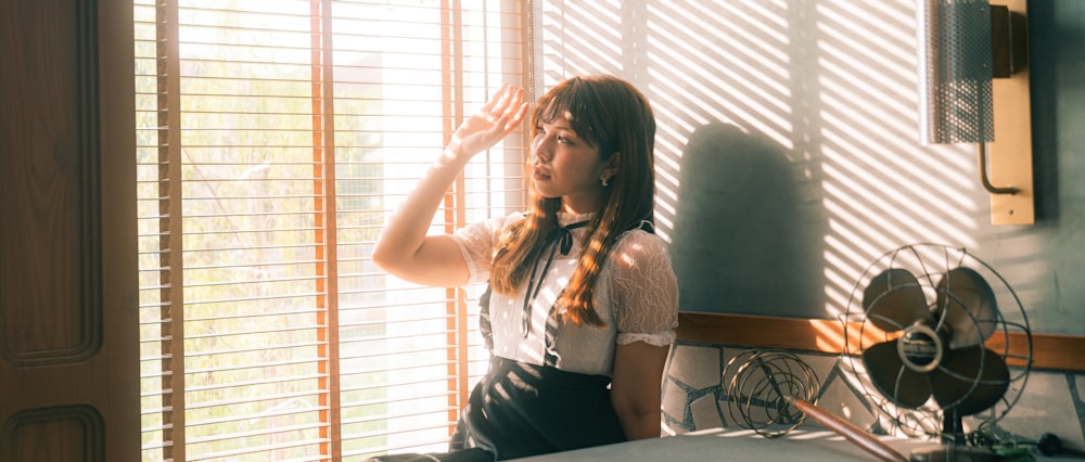 a woman standing in front of a window with blinds