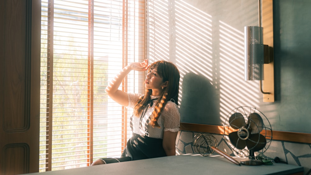 a woman sitting on a counter in front of a window