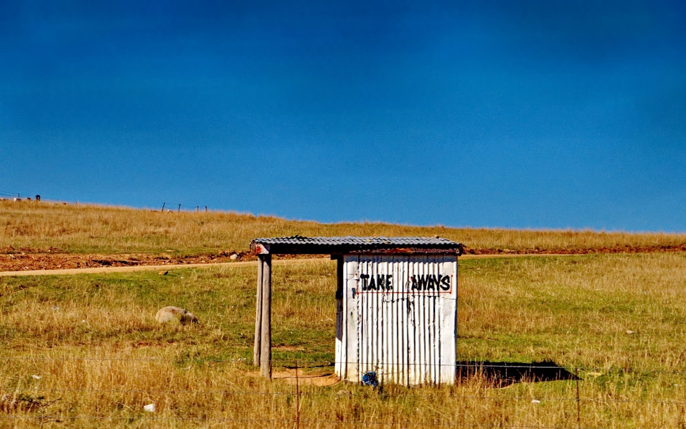 a outhouse in a field with a dirt path