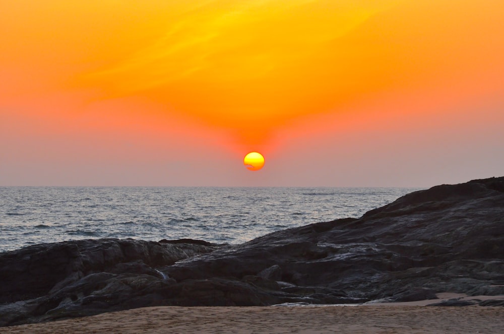 the sun is setting over the ocean on the beach