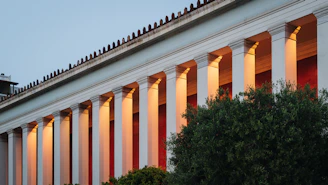 An elegant stone-like outdoor lighting column illuminating a hotel garden at dusk.