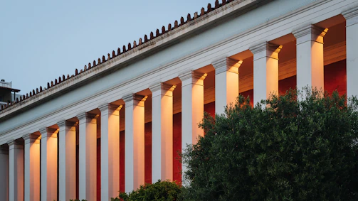 An elegant stone-like outdoor lighting column illuminating a hotel garden at dusk.