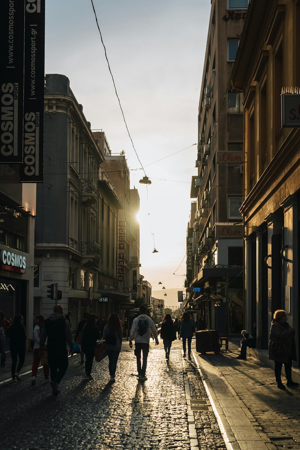 a group of people walking down a street next to tall buildings