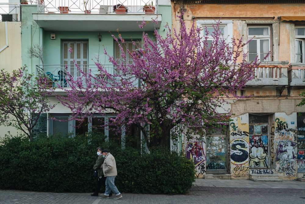 a man walking down a street past a tall building